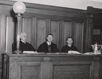 1952 photograph of the College of Law. Left to right: unidentified, Abe Goff, George M. Bell participate in a mock trial with students. Donor: Publications Dept.