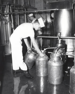 1960 photograph of Dairy Farm and Creamery. Two students use machinery to separate milk. Donor: Photo Center.