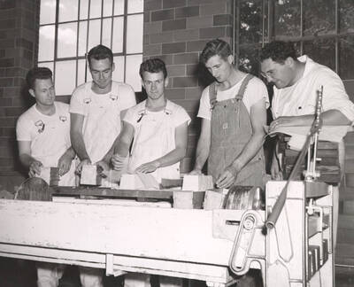 1953 photograph of Dairy Farm and Creamery. Five students examine bricks of freshly made cheese. Donor: Publications Dept.