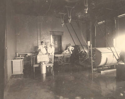 1908 photograph of Dairy Farm and Creamery. Students operate machinery in the Creamery.