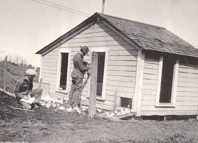 1922 photograph of University Farms. Two people inspect a poultry house.