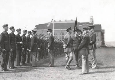 1936 photograph of Military Science Cadets. Cadet battalion in formation during a review. University building in background.