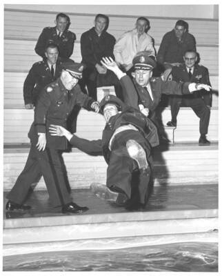 1960 photograph of Military Science Cadets. Cadet thrown into a pool after receiving his wings. Donor: Publications Dept.