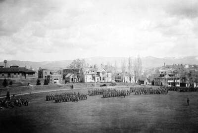 1922 photograph of Military Science Cadets. ROTC battalion in formation in field. University buildings visible in the background.