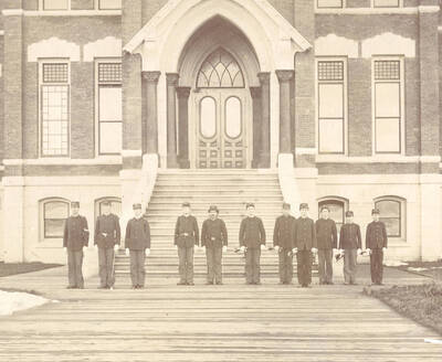 1898 photograph of Military Science Cadets l-r: Charles Simpson, Gilbert Hogue, Mark Barnett, Jesse Rains, Winslow M. Howland, Glen McKinley, unidentified, Guy Wolfe, John Boyd, Elbert Moody, Bob Barkwell. Cadet corps in front of old Administration steps. Donor: Elbert Moody.