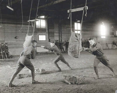 1925 photograph of Military Science Cadets. Military cadets participate in bayonet practice indoors.