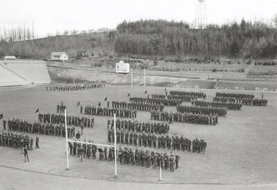 1935 photograph of Military Science Cadets. Military cadets on inspection at MacLean Field. 'I' Tower is visible on the hillside in the background.