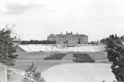 1936 photograph of Military Science Cadets. Military cadets on inspection at MacLean Field. Administration building is visible in the background.