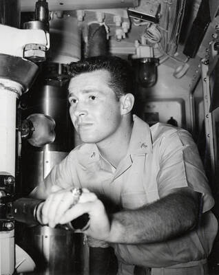 1960 photograph of Naval Science. Midshipman Gary L. Barr at periscope on USS Barbero. Donor: Publications Dept.