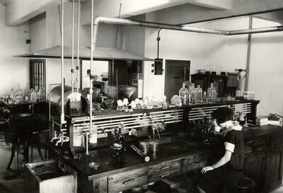 1924 photograph of Bacteriology building. University student studies at her work station.