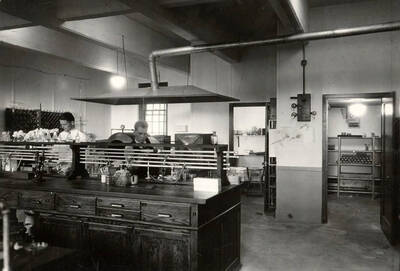 1926 photograph of Bacteriology building. Two students work in the lab.