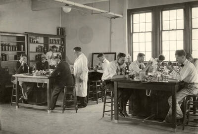 1933 photograph of Bacteriology building. Professor and students work in the lab.