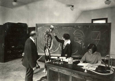 1930 photograph of Zoology building. Professor and student work with a model of a human.