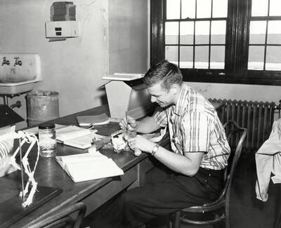 1960 photograph of Zoology building. Mr. Francq dissects a cat at the workstation.
