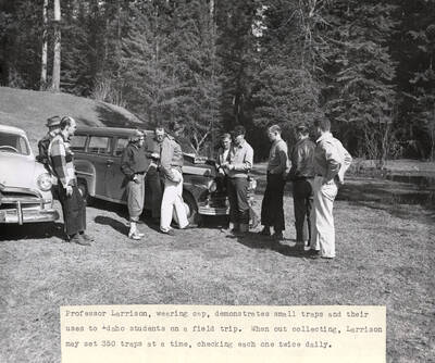 1951 photograph of Zoology building. Professor demonstrates the use of small traps to his students at the start of a field trip.