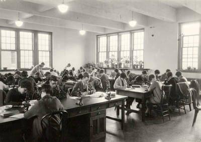 1936 photograph of Botany building. Students work with microscopes in the lab.
