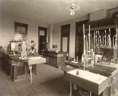 1906 photograph of Agricultural chemistry building. Students work with equipment at lab workstations.
