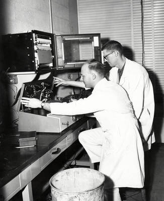 1961 photograph of Agricultural chemistry building. Professor and student work with equipment.