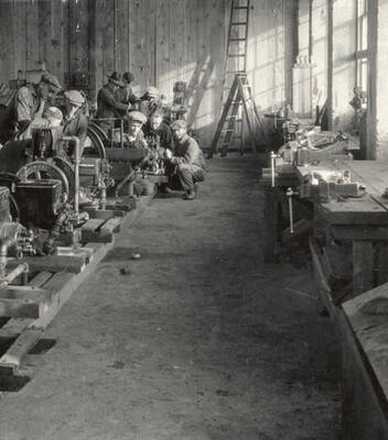 1929 photograph of Agricultural engineering building. Students work on machines in the engineering shop.