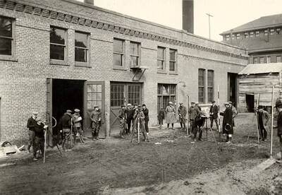 1928 photograph of Agricultural engineering building. Students use surveying equipment.