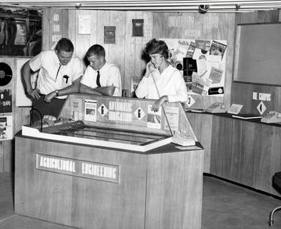 1952 photograph of Agricultural engineering building. Students stand behind an agricultural engineering display.