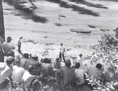 1966 photograph of College of Forestry. Students sitting on a hillside overlooking a lake during the forestry summer camp. Also print. Donor: Fred Johnson.