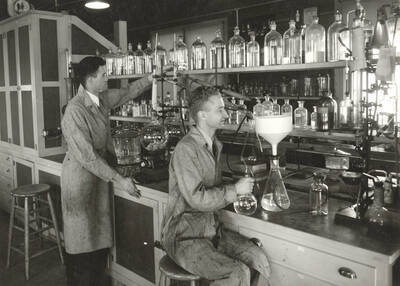 1936 photograph of College of Forestry. McCarthy and Larsen work at lab tables in the wood conversion laboratory. Donor: Publications Dept.