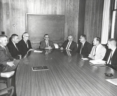 1963-04-19 photograph of College of Forestry. D. Haynes, Bud Jones, Fred Dickinson, Ernest Wohletz, Bob Olin, Edgar Grahn, John Howe, and Dick Just sitting around a polished conference table. Donor: Graduate School.
