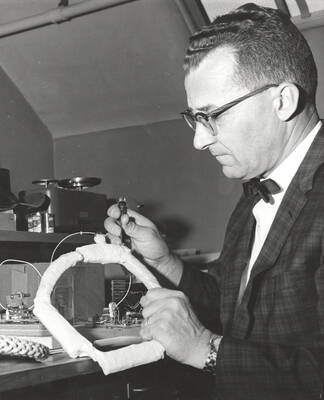1964 photograph of College of Forestry. Kenneth Hungerford examines a blinking light on a deer collar that he designed. Donor: Publications Dept.