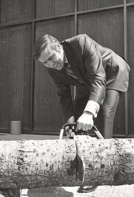 1974 photograph of College of Forestry. John H. Ehrenreich uses a chainsaw to cut a log.