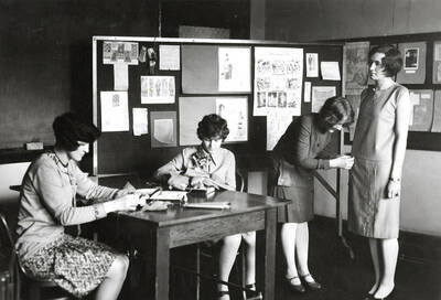 1927 photograph of Home Economics. Students work together to make dresses in class.