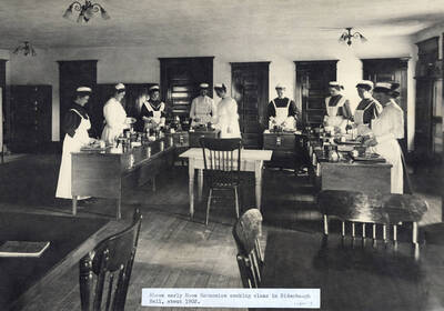 1902 photograph of Home Economics. Students cooking for class in Ridenbaugh Hall.