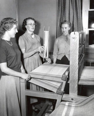 1952 photograph of Home Economics. Students operating a loom during weaving class. Donor: Publications Dept.