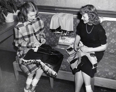 1942 photograph of Home Economics. Two students during a sewing demonstrations. Donor: Publications Dept.