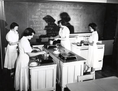1942 photograph of Home Economics. Students cooking Bean Soup Dubois Recipe. Donor: Publications Dept.