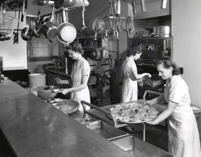 1955 photograph of Home Economics. Students cooking during class. Donor: Publications Dept.