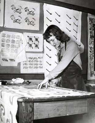 1943 photograph of Home Economics. A student measures cloth in class. Donor: Publications Dept.