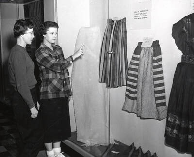 1958 photograph of Home Economics. Two women examine an exhibit of student weaving projects. Donor: Publications Dept.