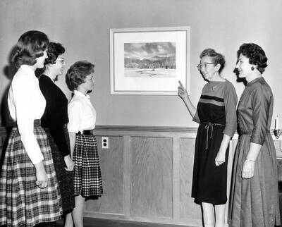 1966 photograph of Home Economics. Students with Marion Featherstone and Gladys Bellinger examine a mounted photograph. Donor: Publications Dept.