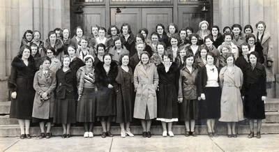 1932 photograph of Home Economics. Students standing together in front of the Administration building.