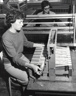 1960 photograph of Home Economics. Students working at looms during weaving class.