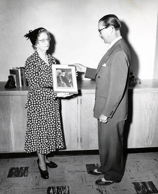 1944 photograph of Music Department. Mrs. Jay Woodworth and Hall Macklin examine a photograph.