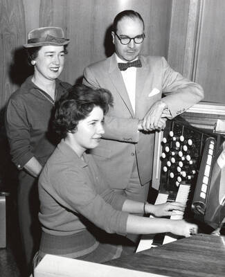 1960 photograph of Music Department. Organ student Kathleen Irwin, her mother Mrs. Claude Irwin, and professor Hall M. Macklin at an organ keyboard.