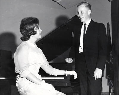 1960 photograph of Music Department. Music students in front of a piano. Donor: Publications Dept.