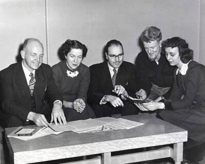 1962-01-03 photograph of Music Department. Elwyn Schwartz, Marion Frykman, Hall Macklin, Rex Eikum, Bonne Allee confer about All American Composers Concert