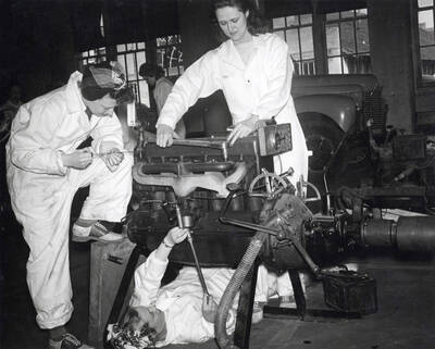 1944 photograph of College of Engineering. Female students work on an engine for the Women's auto mechanics course during World War II.