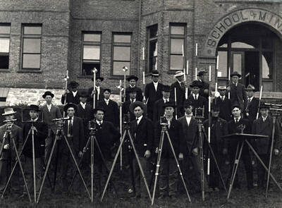1907 photograph of College of Engineering. Students with surveying equipment in front of the School of Mines building.
