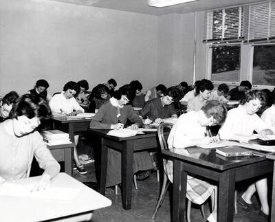 1961 photograph of College of Business Administration. Students at desks studying shorthand. Donor: Photo Center.
