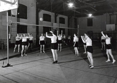 1936 photograph of Physical Education. Women's volleyball inside the gymnasium.