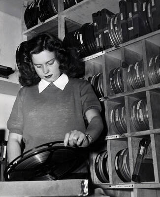1951 photograph of Audio Visual Aids Service. A student examines a reel of film.